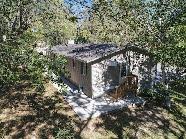 view of side of home with a patio area, a shingled roof, and a chimney