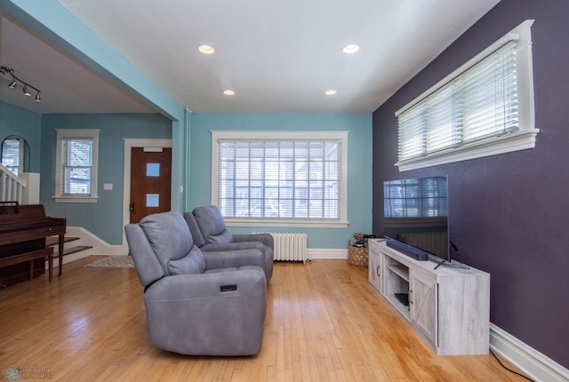 708 1st St N, Fargo, ND 58102 - living room featuring baseboards, light wood-style floors, radiator heating unit, and stairway
