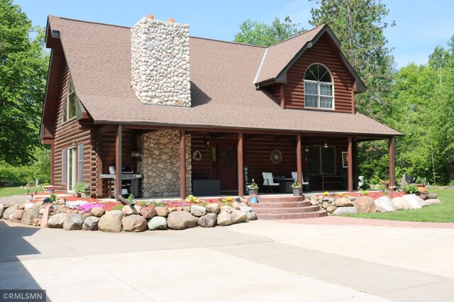 14638 State Highway 70, Pine City, MN 55063 - log-style house featuring a porch, a chimney, a shingled roof, and log exterior