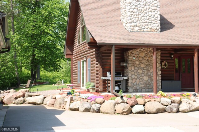 14638 State Highway 70, Pine City, MN 55063 - view of front of house featuring log exterior, roof with shingles, and a patio area
