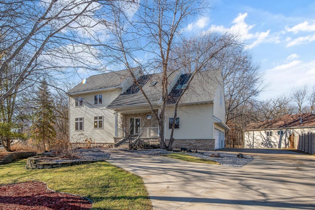 traditional-style house featuring an attached garage, concrete driveway, and stone siding