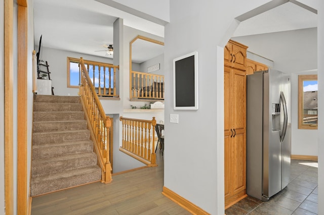 stairs featuring baseboards, a ceiling fan, and wood finished floors