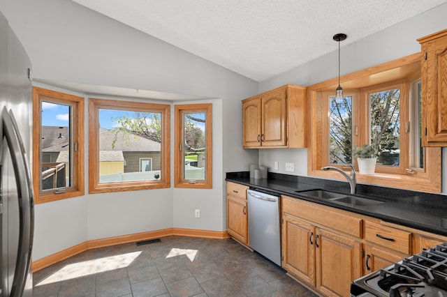 kitchen with visible vents, lofted ceiling, dark countertops, a sink, and stainless steel appliances