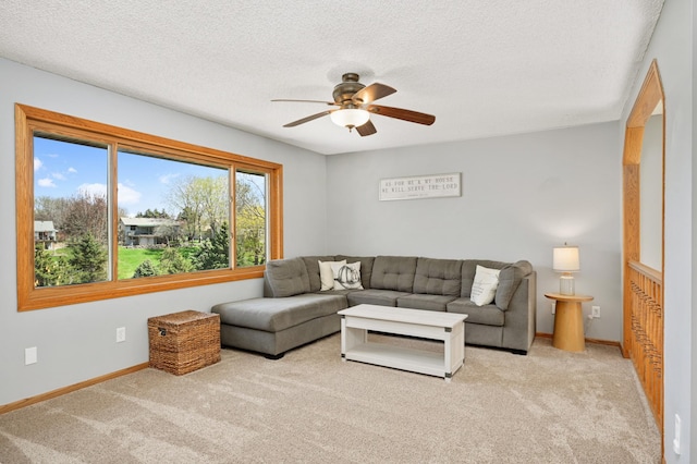 living area with carpet flooring, a ceiling fan, baseboards, and a textured ceiling