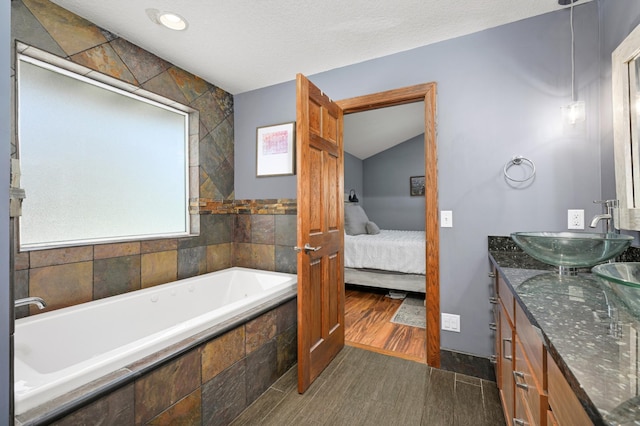 ensuite bathroom with a sink, ensuite bathroom, a garden tub, and double vanity