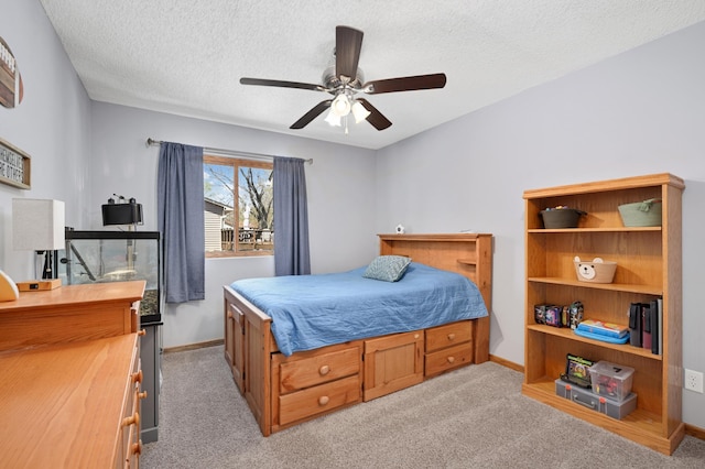 bedroom featuring baseboards, a textured ceiling, ceiling fan, and light carpet