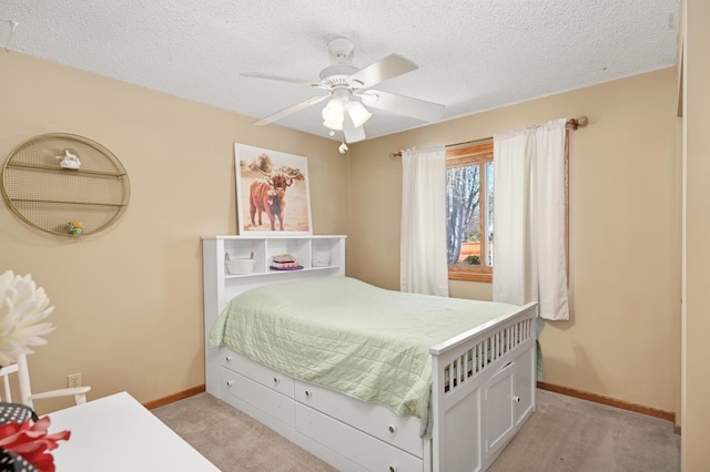 bedroom with baseboards, a ceiling fan, a textured ceiling, and light colored carpet