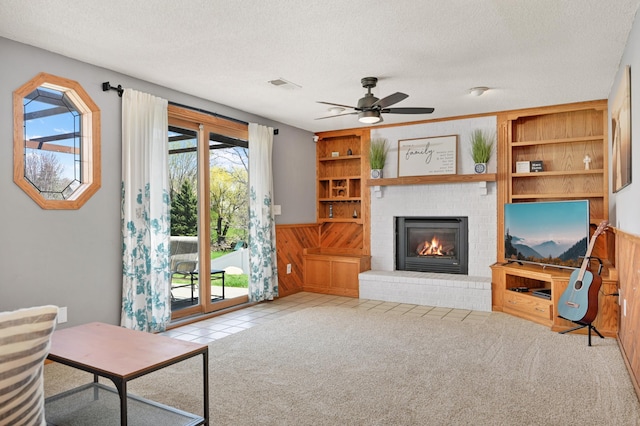carpeted living room featuring visible vents, a ceiling fan, a textured ceiling, and a brick fireplace