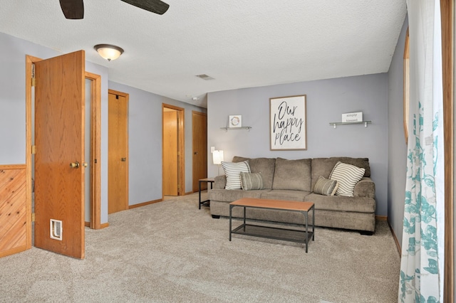 carpeted living room with baseboards, a ceiling fan, a textured ceiling, and visible vents