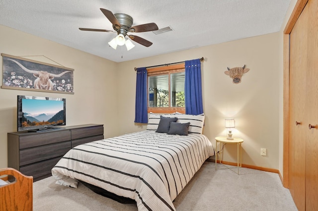 bedroom featuring visible vents, light carpet, baseboards, ceiling fan, and a textured ceiling