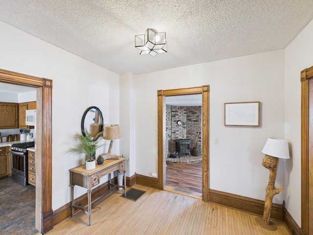 hall with a textured ceiling, baseboards, and dark wood-style floors