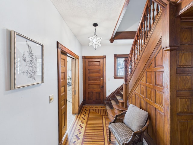entryway featuring a chandelier, stairs, baseboards, and a textured ceiling