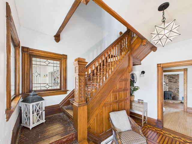 staircase featuring an inviting chandelier, wood-type flooring, beam ceiling, and baseboards