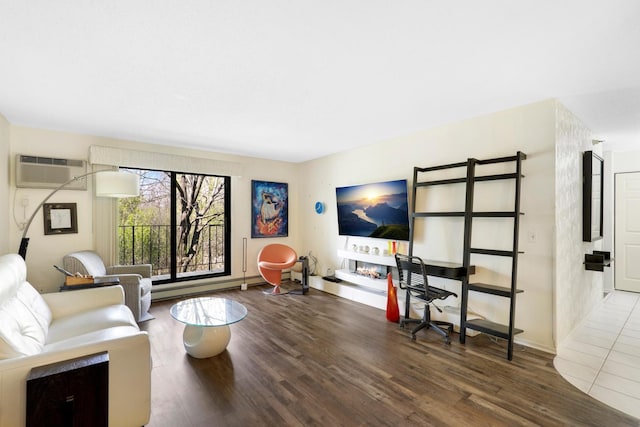 living room featuring a wall unit AC, wood finished floors, and baseboards