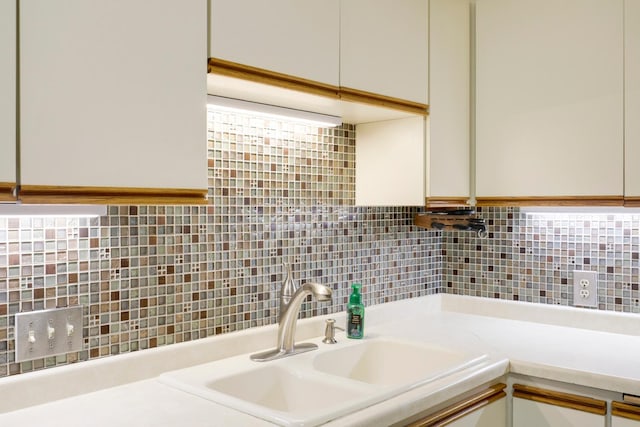 kitchen with a sink, backsplash, light countertops, and white cabinetry