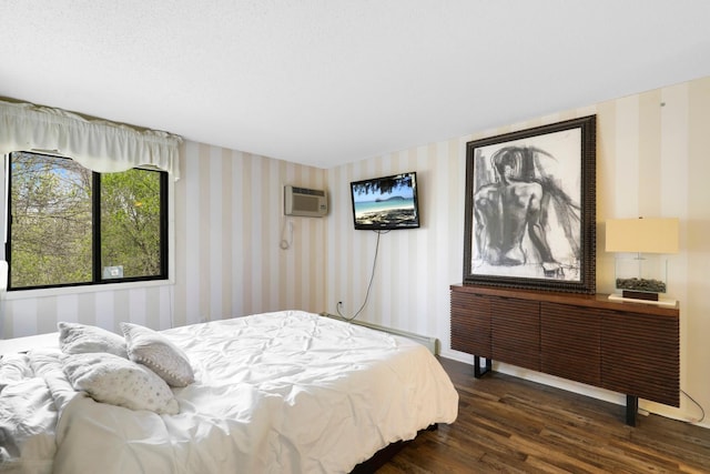 bedroom with wallpapered walls, dark wood-type flooring, a wall mounted air conditioner, radiator, and a baseboard heating unit