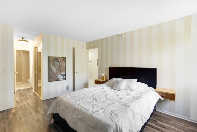 bedroom featuring wood finished floors, baseboards, and ensuite bath