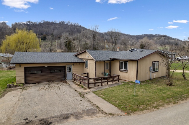 ranch-style house featuring an attached garage, driveway, a mountain view, and roof with shingles