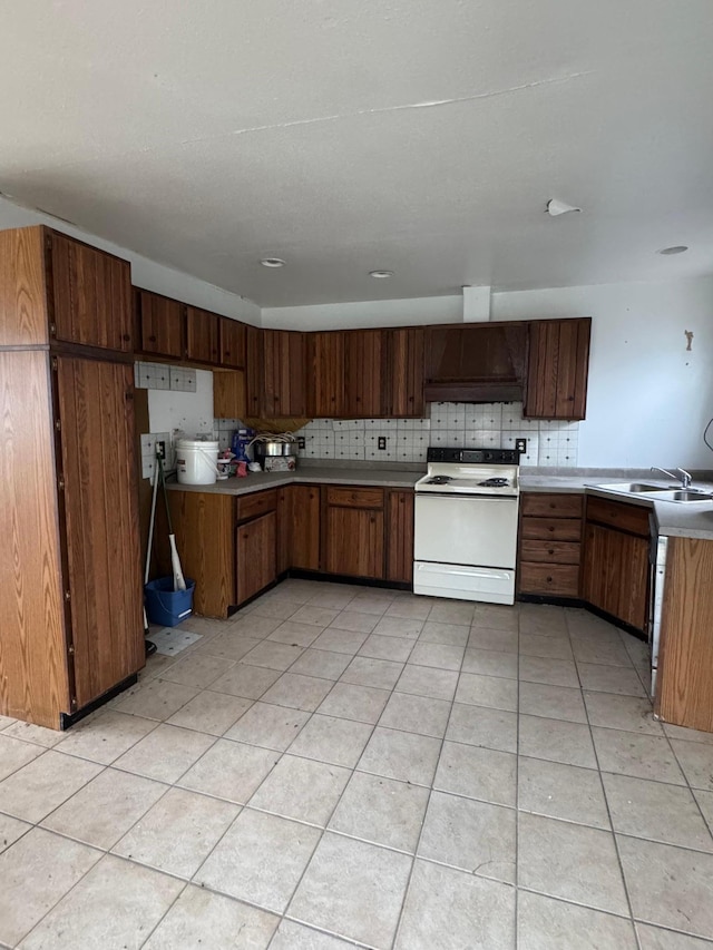 kitchen featuring white electric range, light countertops, a sink, a peninsula, and custom exhaust hood