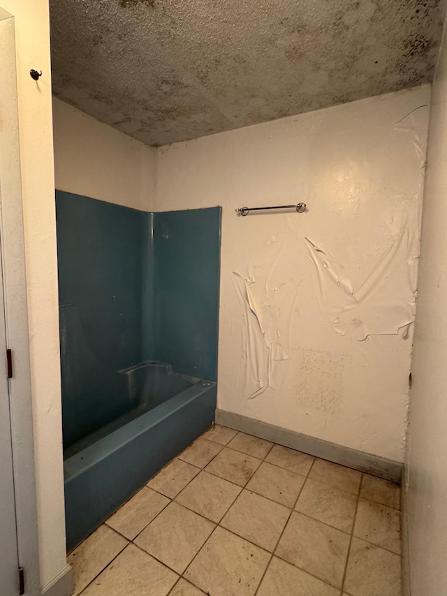 full bathroom featuring a bath, a textured ceiling, tile patterned floors, and baseboards