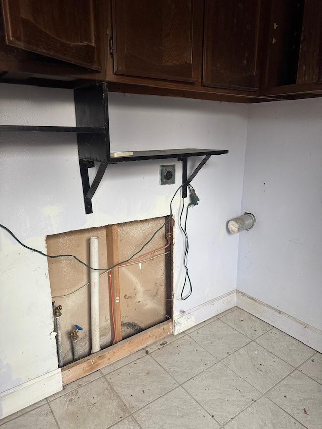 clothes washing area featuring cabinet space, baseboards, electric dryer hookup, and light tile patterned floors