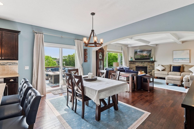 3209 Symphony Ct, Chaska, MN 55318 - dining room featuring dark wood finished floors, a chandelier, beamed ceiling, arched walkways, and a fireplace