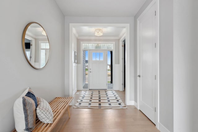 entryway featuring an inviting chandelier, wood finished floors, ornamental molding, and baseboards