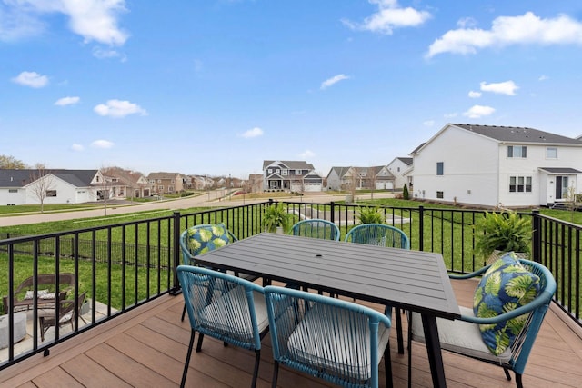 wooden terrace featuring a lawn, a residential view, and outdoor dining area