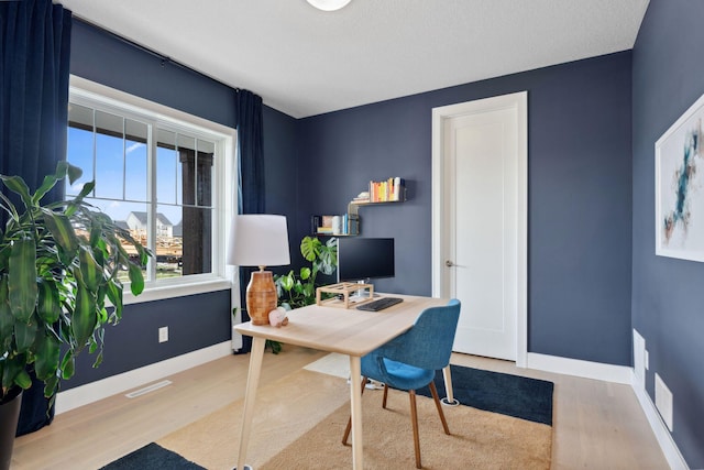 office space with visible vents, wood finished floors, and baseboards