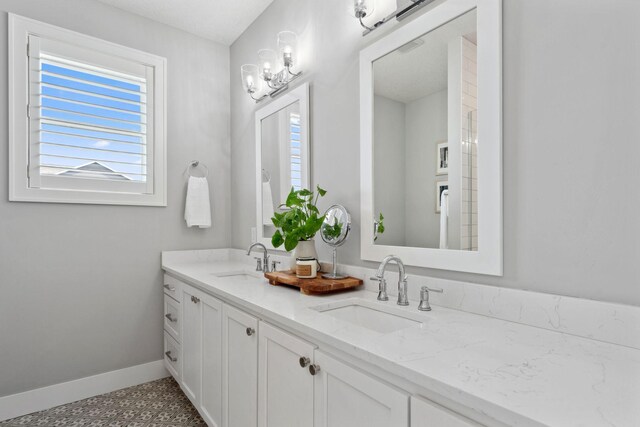 bathroom featuring double vanity, baseboards, and a sink