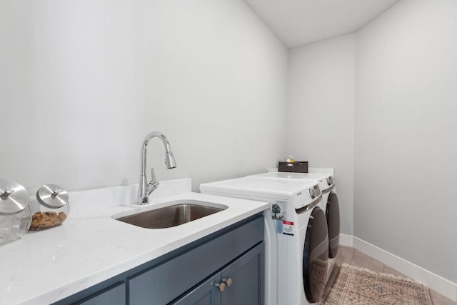 clothes washing area featuring light tile patterned floors, a sink, baseboards, washer and clothes dryer, and cabinet space