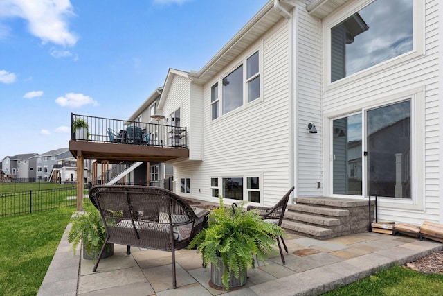 back of property featuring stairway, a patio area, a lawn, a deck, and fence
