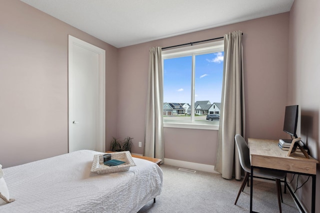 bedroom with baseboards, visible vents, and light carpet