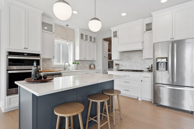 kitchen featuring tasteful backsplash, stainless steel appliances, white cabinets, and a sink