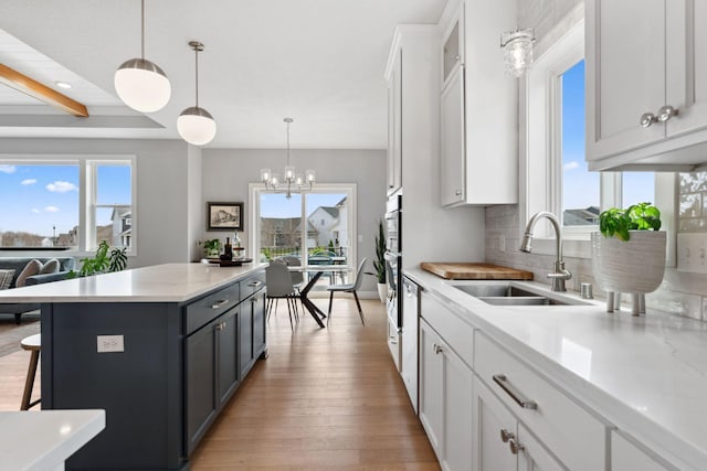 kitchen with a sink, white cabinets, a wealth of natural light, and light wood-type flooring