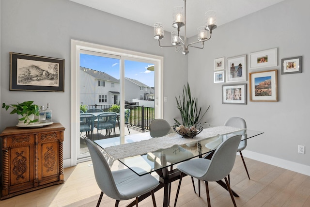dining space with light wood finished floors, a notable chandelier, and baseboards