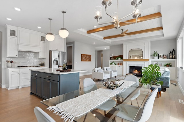 dining space featuring recessed lighting, a tile fireplace, light wood-style flooring, and a raised ceiling