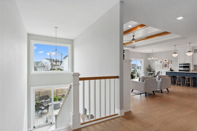 hallway featuring recessed lighting, hardwood / wood-style floors, beamed ceiling, an upstairs landing, and a notable chandelier
