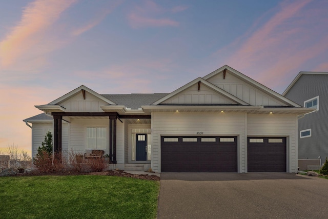view of front of home featuring a front yard, board and batten siding, aphalt driveway, and a garage