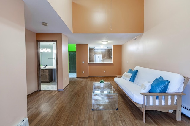 living area with baseboards, wood finished floors, and baseboard heating