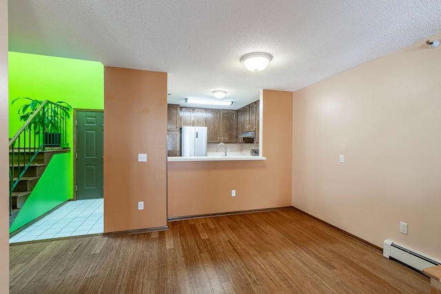 interior space featuring baseboard heating, baseboards, wood finished floors, and stairs