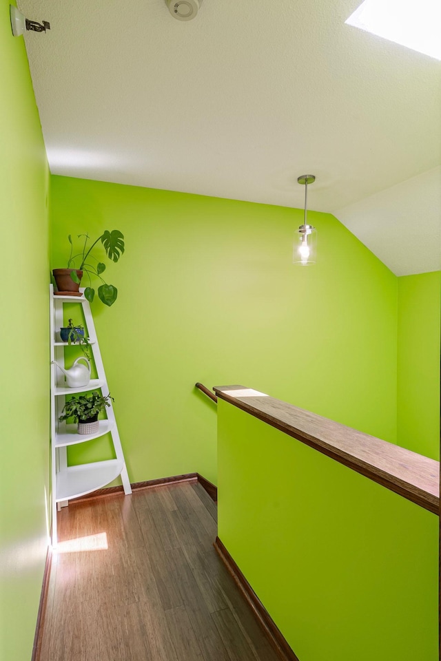 hallway with lofted ceiling, baseboards, and dark wood finished floors