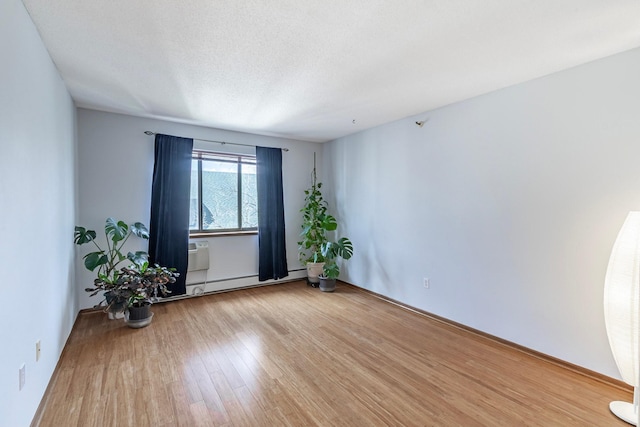 spare room with a baseboard heating unit and wood finished floors