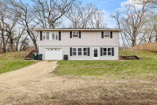exterior space featuring an attached garage, fence, dirt driveway, a front lawn, and stairs