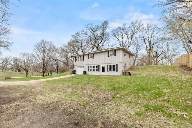 view of front of property with board and batten siding, a front yard, driveway, and an attached garage