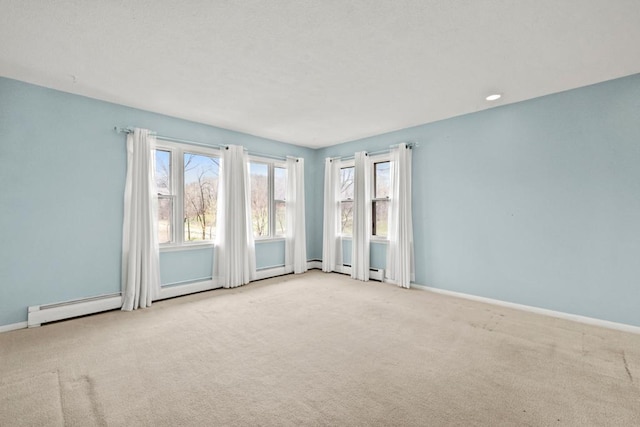 unfurnished room with a baseboard heating unit, carpet, and baseboards
