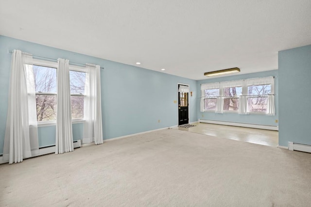 unfurnished living room with a baseboard heating unit, a wealth of natural light, carpet floors, and baseboards