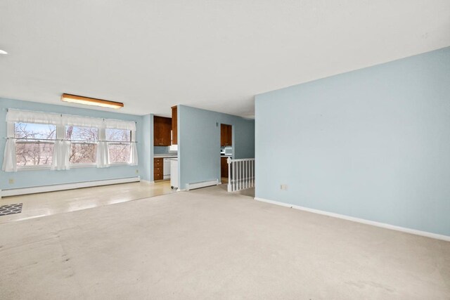 unfurnished living room with baseboard heating, light colored carpet, and baseboards