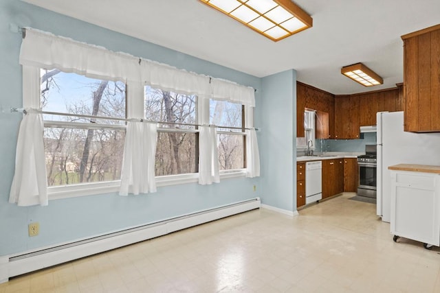 kitchen with a healthy amount of sunlight, white appliances, a baseboard heating unit, light countertops, and a sink