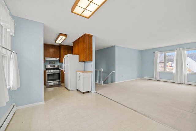 kitchen featuring a baseboard heating unit, light countertops, baseboards, freestanding refrigerator, and gas range